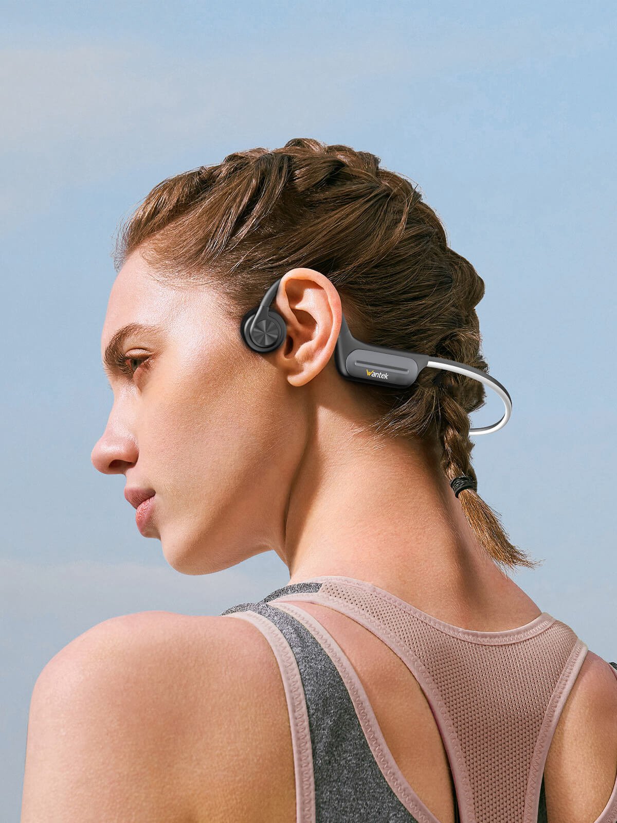 Woman wearing gray Wantek open-ear bone-conduction headphones outdoors