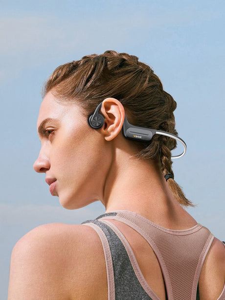 Woman wearing gray Wantek open-ear bone-conduction headphones outdoors