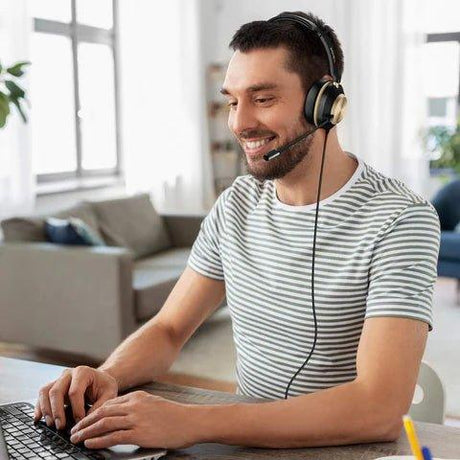 Man wearing Wantek wired headset with microphone working on laptop in bright coworking space