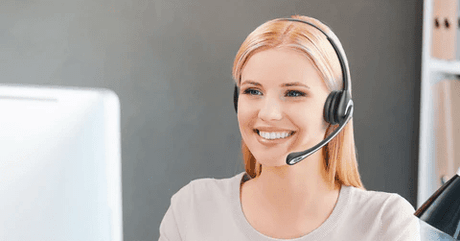 Smiling woman wearing black wired headset with microphone in modern office setting