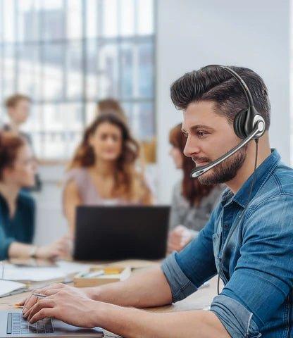 Customer service representative wearing Wantek wired headset working in bright office with team
