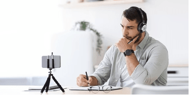 man wearing Wantek wired headset with built-in microphone, working and recording on smartphone in bright office