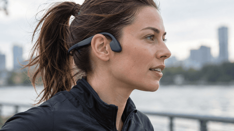 Runner wearing an open-ear bone conduction headset with transducer pads resting in front of the ears