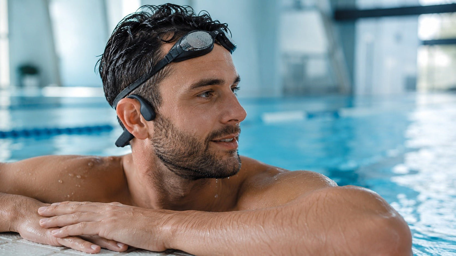 Swimmer wearing waterproof bone conduction headphones at the pool edge
