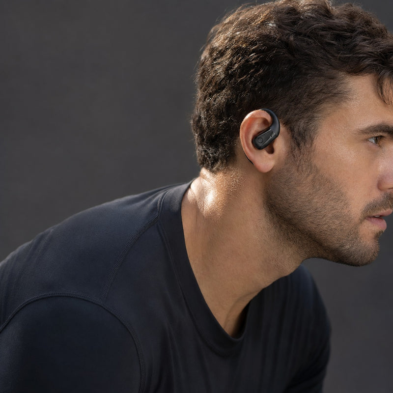 Adult wearing Wantek OBT030 clip-on earbuds with a secure fit during an outdoor workout
